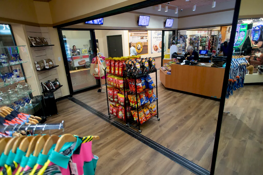 Wood-look flooring in a gift shop with employee behind checkout counter and customer browsing clothing racks.